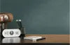 A desk with a clock, pencils, and a notebook against a dark teal wall. Produktbild-Vorschau