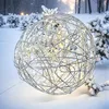 A silver wire sphere with lights, sitting in the snow with snow-covered trees in the background. Produktbild-Vorschau