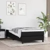 A black boxspring bed frame with a mattress and a grey throw blanket is shown in a room with two framed pictures on the wall and a large potted plant. Produktbild-Vorschau