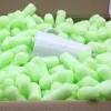 A white mug is packed in green packing peanuts inside a cardboard box. Produktbild-Vorschau