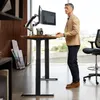 A man is standing at a height-adjustable desk in an office setting, working on a computer. Náhľad obrázku produktu