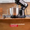 A black stand mixer with a silver bowl is shown on a wooden countertop, highlighting its suction feet. Produktbild-Vorschau