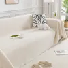 A cream-colored sofa with a throw blanket draped over it, featuring decorative pillows and a small cat figurine. Produktbild-Vorschau