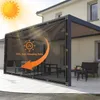 A black PVC tarp is attached to a modern pergola, providing shade and protection from the sun. The tarp has grommets for attachment and features an orange arrow graphic indicating sun protection. Outdoor furniture is visible under the pergola. Náhled obrázku produktu