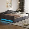 A gray upholstered daybed with tufted detailing and blue LED lighting along the base, set in a bedroom with curtains and a framed picture on the wall. Anteprima dell’immagine prodotto