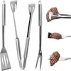 A set of stainless steel grilling utensils, including a spatula, tongs, and a fork, displayed against a white background. Close-up shots of a piece of grilled meat being handled by the utensils are also shown. Anteprima dell’immagine prodotto