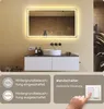 A bathroom scene featuring a large illuminated mirror above a vanity with a sink. Text overlays provide information about lighting features and a wall switch. Produktbild-Vorschau