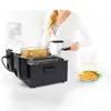 A person is operating a black deep fryer with French fries inside. Náhľad obrázku produktu