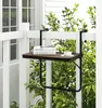A small table attached to a balcony railing with a book and a cup of coffee on it. Podgląd zdjęcia produktu