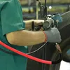 A person in a green uniform is using a pneumatic tool connected to a red hose, likely for tire inflation or repair. Produktbild-Vorschau