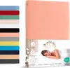 A product image showing a folded pink fitted sheet and a stack of various colored fitted sheets on the left, with marketing information and a model sleeping on a bed on the right. Produktbild-Vorschau