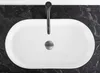 A top-down view of a white oval basin sink with a black faucet and drain. Anteprima dell’immagine prodotto