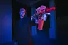 A person holding a toy gun in a dimly lit outdoor area with blue and red lighting. Voir les images du produit