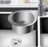 A close-up view of a stainless steel sink strainer basket and faucet in a modern kitchen. Náhled obrázku produktu