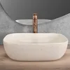 A beige terrazzo countertop sink with a copper faucet is shown in a bathroom setting. Anteprima dell’immagine prodotto