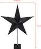 A black star-shaped lamp with cutouts, standing on a black square base, with dimensions indicated. Produktbild-Vorschau