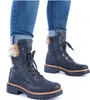 A pair of black Rieker women's lace-up boots with fur trim, worn with cuffed blue jeans. Anteprima dell’immagine prodotto