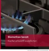 Close-up of a gas stove burner with blue flames, overlaid with marketing text. Produktbild-Vorschau