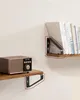 Two wooden shelves are mounted on a white wall, each supported by black metal brackets. The top shelf displays a stack of books, while the bottom shelf holds a vintage-style radio. Náhled obrázku produktu