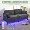 A modern gray sofa with LED lighting underneath, shown in a living room setting with a remote control and feature icons. Produktbild-Vorschau