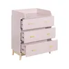 A pink dresser with three drawers, one of which is partially open, and wooden legs, set against a white background. Podgląd zdjęcia produktu