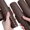 Hands are shown connecting two brown plastic garden edging pieces together. Náhled obrázku produktu