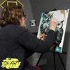 A woman is painting an owl picture on a canvas on an easel. Produktbild-Vorschau