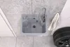 A sink in a garage setting with a tire and towel nearby. Anteprima dell’immagine prodotto