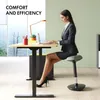 A woman in a business suit sits on an adjustable stool at a standing desk, working on a laptop. Anteprima dell’immagine prodotto