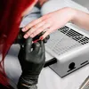A person is getting their nails done with red nail polish, with a nail dust collector in the background. Anteprima dell’immagine prodotto