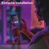 A person is holding a smartphone with the Calex app open, in a dimly lit room with purple and blue lighting. Produktbild-Vorschau