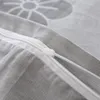 A close-up shot of a zipper on a gray fabric with a white floral pattern. Produktbild-Vorschau