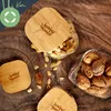 A collection of glass jars with bamboo lids filled with nuts and pistachios, arranged on a wooden surface. Produktbild-Vorschau