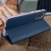A person's hand is seen interacting with a blue flip case for a smartphone, which is placed on a wooden surface. Náhled obrázku produktu