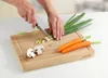A person is chopping vegetables on a bamboo cutting board. Anteprima dell’immagine prodotto
