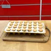 A baking tray filled with cookies on a wooden surface, with a red background. Náhled obrázku produktu