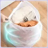 A person is holding open a white mesh laundry bag filled with clothes, with glowing blue rings around the bag. Produktbild-Vorschau