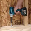 A hand holding a Makita impact wrench drilling into a wooden beam. Podgląd zdjęcia produktu