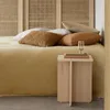 A bed with several pillows and a small wooden side table next to it. Anteprima dell’immagine prodotto