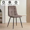 A brown upholstered dining chair with black metal legs is shown in a room with a white wall and wooden floor. Produktbild-Vorschau