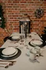 A table set for a festive meal with plates, cutlery, mugs, candles, and a lantern. Náhľad obrázku produktu