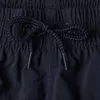 A close-up view of a dark blue drawstring tie on a pair of shorts. Produktbild-Vorschau