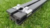 A close-up shot of two black composite deck boards held together by a silver metal clip, resting on green grass. Produktbild-Vorschau