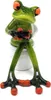 A ceramic figurine of a frog sitting on a toilet, holding a black object. Produktbild-Vorschau