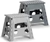 Two folding step stools, one in dark gray and one in light gray, are shown against a white background. They are positioned diagonally to each other, with the light gray stool in the foreground and the dark gray stool slightly behind and to the right. Náhľad obrázku produktu