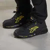 A person wearing black pants and black and yellow U-Power safety shoes. Náhled obrázku produktu