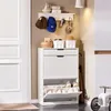 A white shoe cabinet with multiple compartments and shelves, placed in an entryway next to a white door. The top shelf has decorative items and storage baskets. Anteprima dell’immagine prodotto