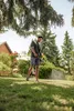 A man is spraying a lawn with a Kärcher Akku-Drucksprüher PSU 4-18 in a garden. Produktbild-Vorschau