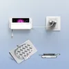 A smartphone is mounted on a wall and charging, with a charging cable plugged into a wall socket. Another charging accessory is shown below. Produktbild-Vorschau