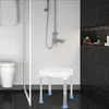 A shower stool is placed in a modern bathroom setting, with a shower running. Produktbild-Vorschau